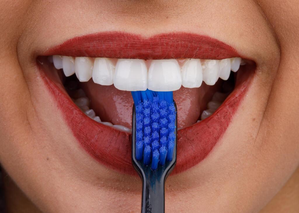 Mulher demonstrando como escovar os dentes corretamente com escova dental durante a higiene bucal