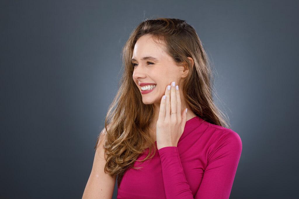 Paciente com dor de dente antes do tratamento de canal, segurando a bochecha devido à infecção na polpa dentária.