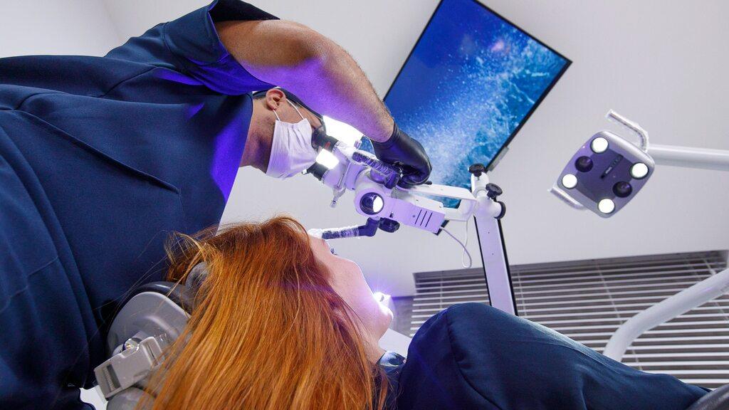 Dentista realiza higienização dos dentes com equipamentos profissionais durante atendimento em consultório.