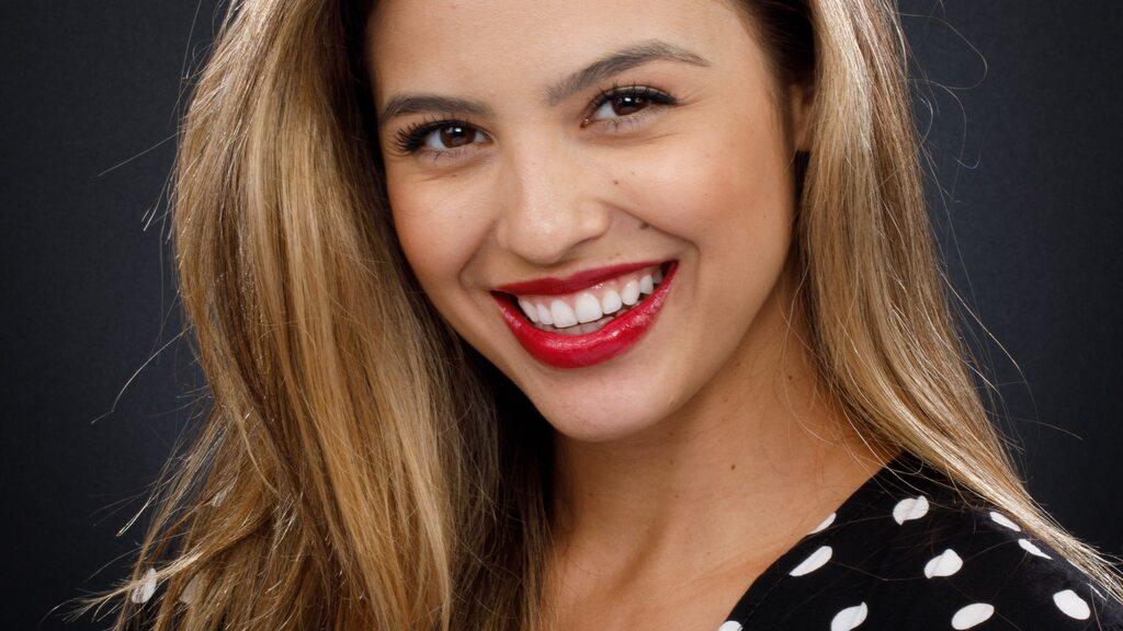 Mulher sorrindo com dentes claros e alinhados, mostrando os resultados do clareamento dental na Orthos Odontologia.