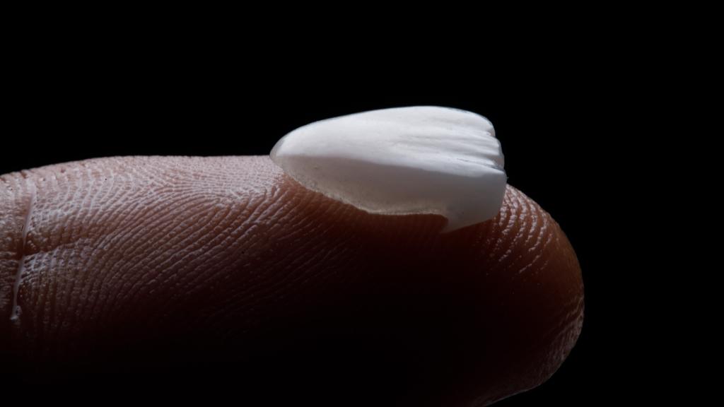 Faceta sobre a ponta do dedo, ilustrando a diferença entre faceta de porcelana ou resina no tratamento.