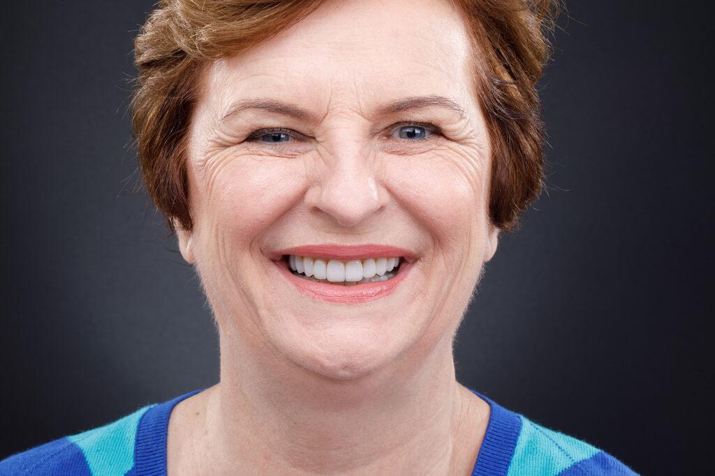 Mulher sorrindo em retrato frontal, mostrando resultado estético odontológico realizado pela Orthos Odontologia.