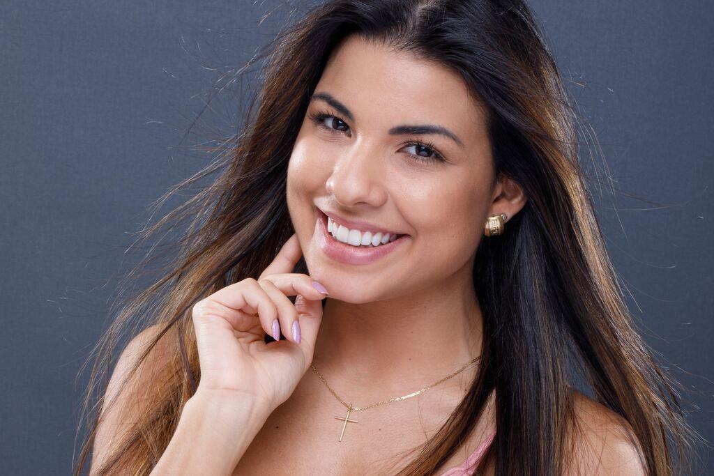 Mulher sorrindo com dentes claros e alinhados, representando cuidados e conservação de facetas de porcelana.